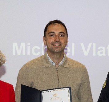 Michael, a graduate program participant, smiling holding a certificate​
